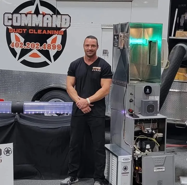 Command Heating owner standing with the branded service trailer and HVAC equipment